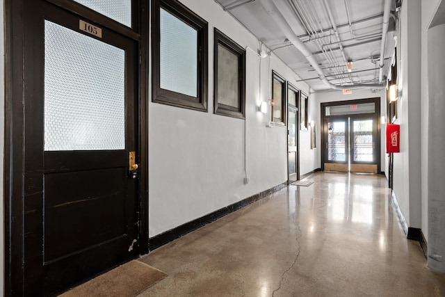 hall with baseboards and concrete floors
