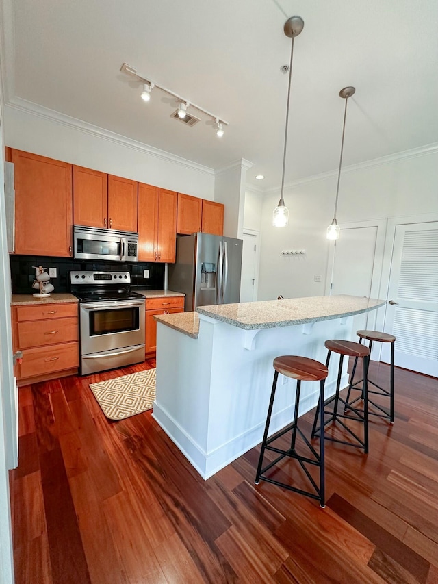 129 Walnut St # 122, Chattanooga, TN 37403 - kitchen featuring crown molding, dark wood finished floors, brown cabinetry, appliances with stainless steel finishes, and decorative backsplash