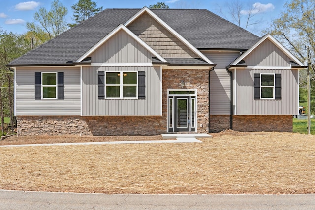 view of front of house with stone siding, board and batten siding, and roof with shingles
