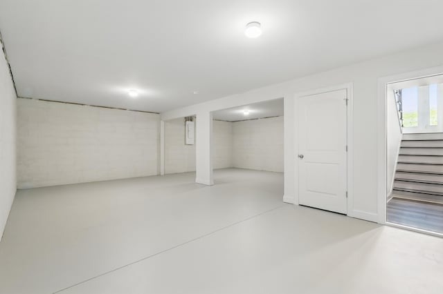 basement featuring concrete block wall and stairway