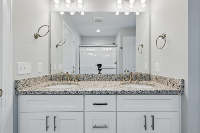 full bathroom featuring double vanity, a sink, a shower with door, and visible vents