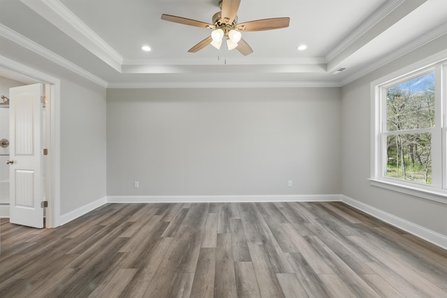 empty room featuring baseboards, wood finished floors, and a raised ceiling