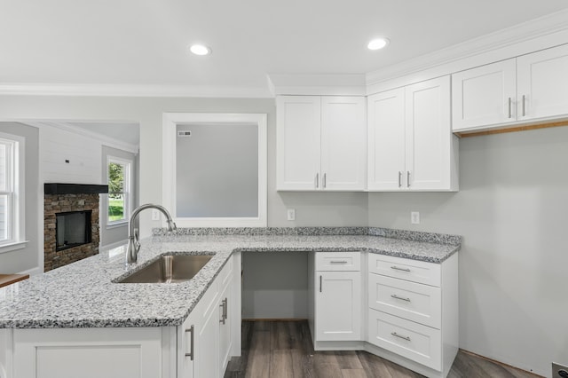 kitchen featuring white cabinets, a peninsula, dark wood finished floors, a sink, and light stone counters