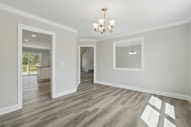 unfurnished dining area featuring baseboards, ornamental molding, wood finished floors, and a chandelier