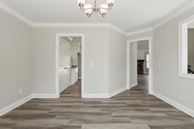 unfurnished dining area featuring baseboards, ornamental molding, wood finished floors, and a chandelier