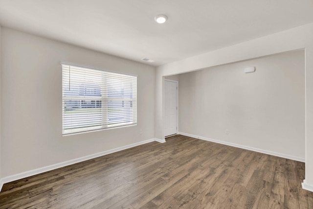 spare room featuring baseboards and dark wood-style flooring