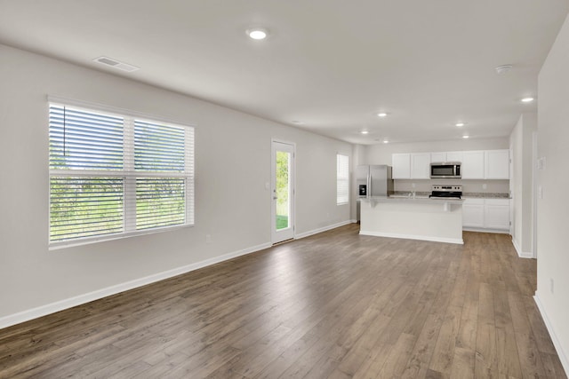 unfurnished living room featuring baseboards, visible vents, recessed lighting, and wood finished floors