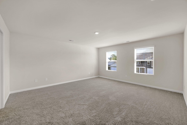 carpeted spare room featuring baseboards and visible vents