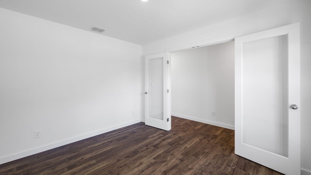 empty room with baseboards, dark wood-style floors, and visible vents