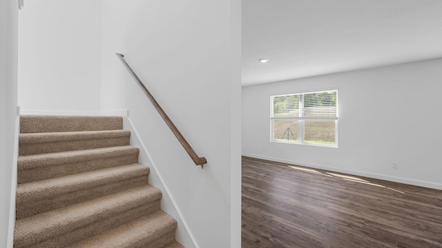 stairway with baseboards, wood finished floors, and recessed lighting