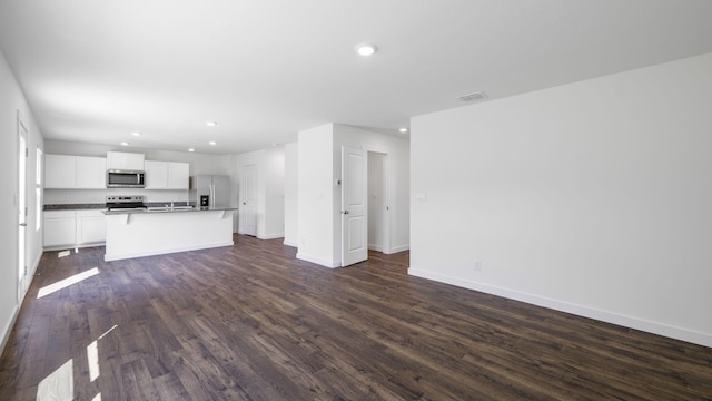 unfurnished living room featuring dark wood-style flooring, visible vents, baseboards, and recessed lighting