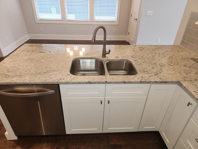 kitchen with white cabinetry, a sink, light stone countertops, and stainless steel dishwasher