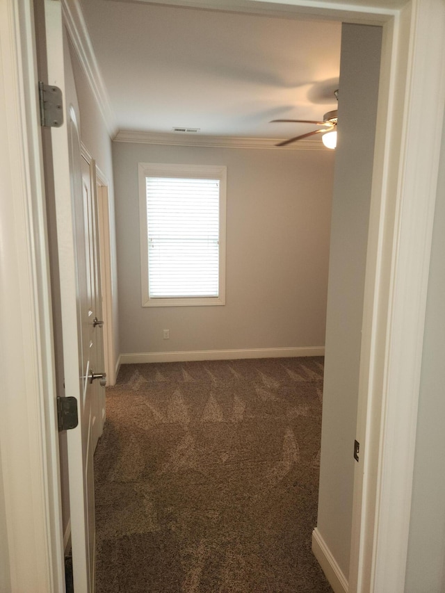 carpeted spare room with baseboards, ceiling fan, visible vents, and crown molding