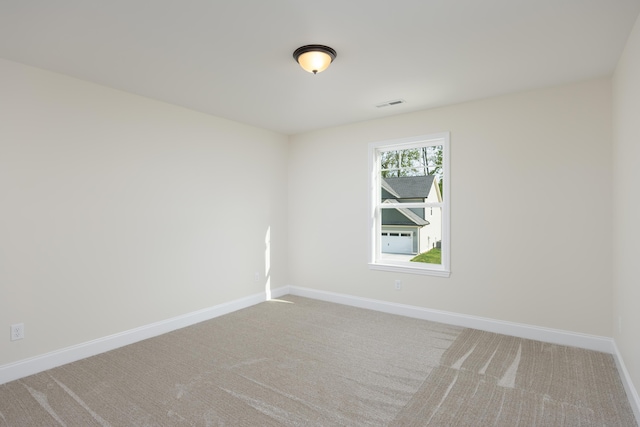 carpeted spare room featuring visible vents and baseboards