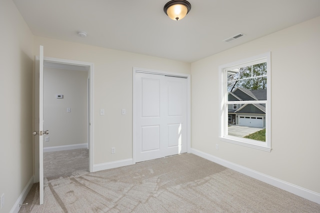 unfurnished bedroom with visible vents, baseboards, a closet, and carpet flooring