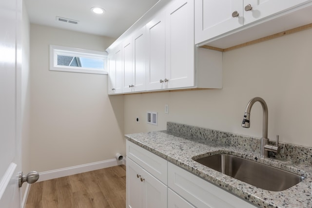 clothes washing area with visible vents, washer hookup, a sink, light wood finished floors, and cabinet space