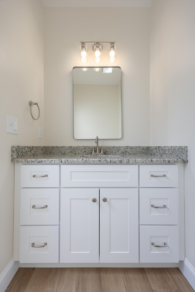 bathroom with baseboards, vanity, and wood finished floors