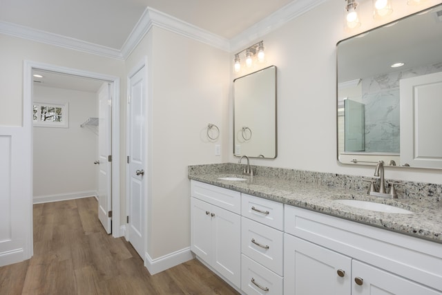 bathroom featuring double vanity, a sink, crown molding, and wood finished floors