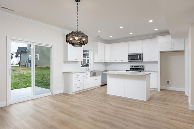 kitchen featuring visible vents, a sink, ornamental molding, stainless steel appliances, and decorative backsplash