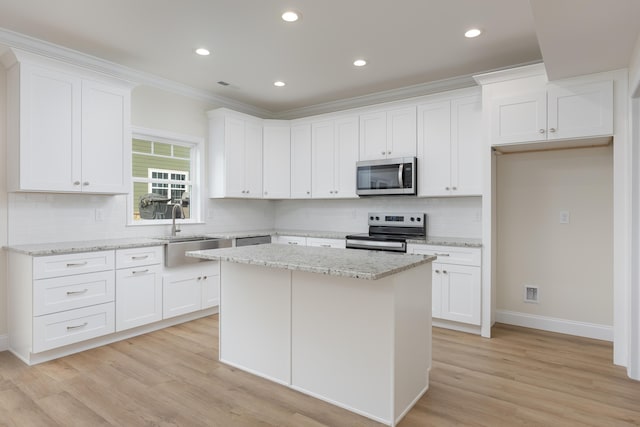 kitchen with a sink, decorative backsplash, appliances with stainless steel finishes, and white cabinetry