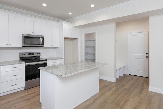 kitchen featuring white cabinets, light wood-style floors, ornamental molding, and appliances with stainless steel finishes