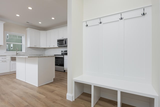 kitchen featuring stainless steel appliances, tasteful backsplash, light wood-type flooring, and crown molding