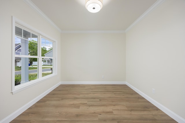 spare room featuring baseboards, crown molding, and wood finished floors