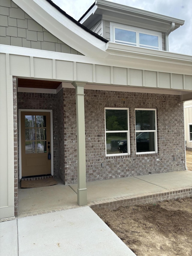 doorway to property with covered porch and brick siding
