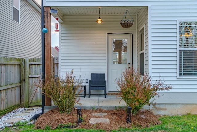 entrance to property featuring covered porch and fence