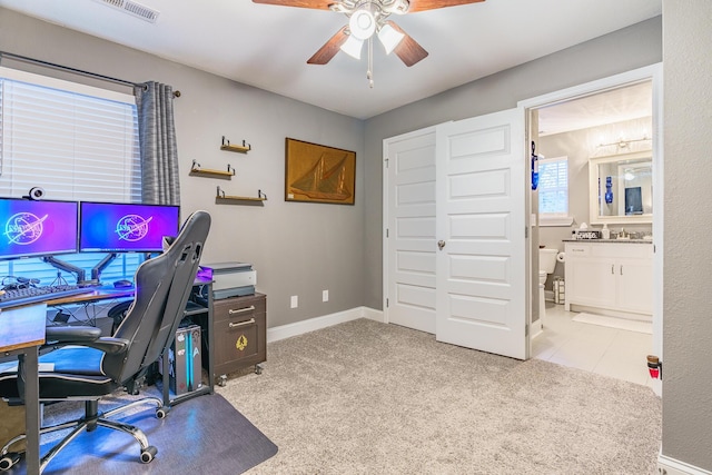 carpeted office featuring a ceiling fan, a sink, and baseboards