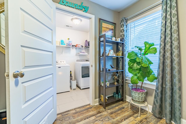 clothes washing area featuring washing machine and clothes dryer and wood finished floors