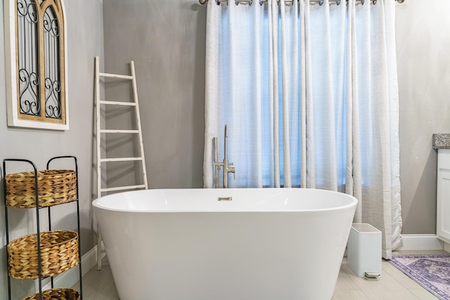 bathroom with baseboards, a freestanding tub, and tile patterned flooring