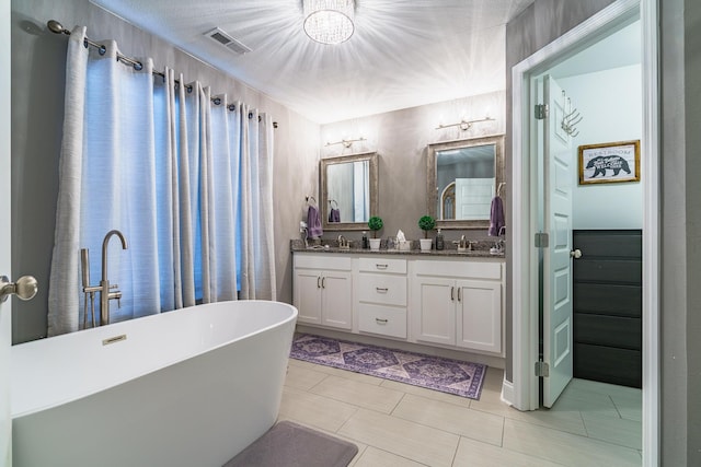 bathroom featuring a chandelier, double vanity, a freestanding tub, and tile patterned floors
