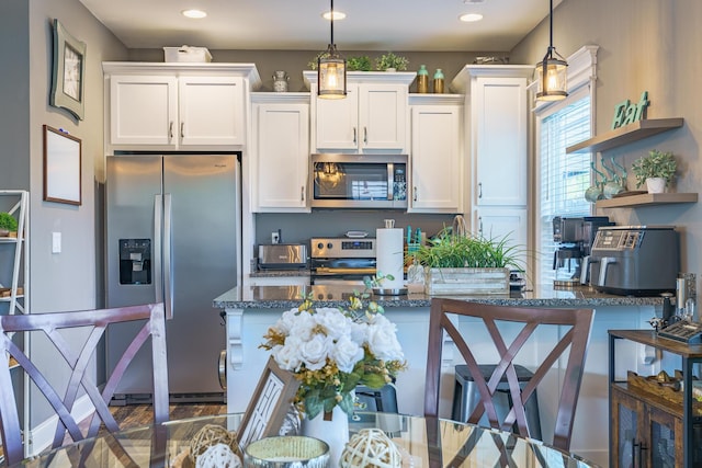kitchen featuring appliances with stainless steel finishes, white cabinetry, dark stone countertops, decorative light fixtures, and recessed lighting