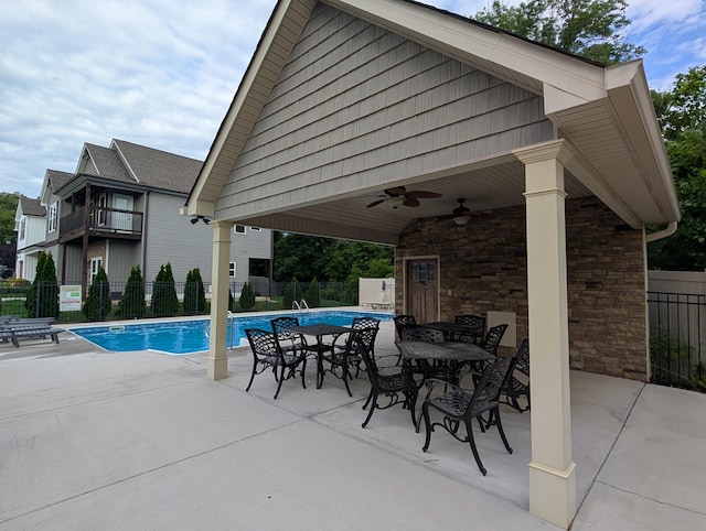 view of swimming pool with fence, a ceiling fan, a patio area, and outdoor dining space