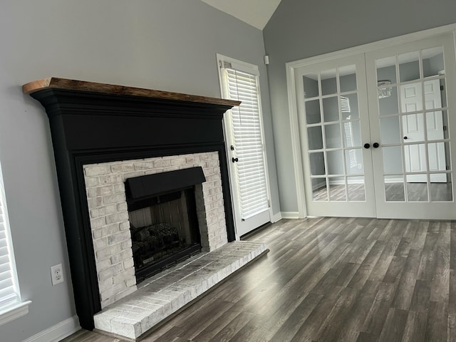 unfurnished living room with lofted ceiling, wood finished floors, a fireplace, baseboards, and french doors