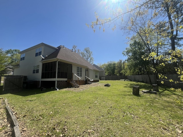 view of yard with entry steps, a fire pit, a fenced backyard, and a sunroom