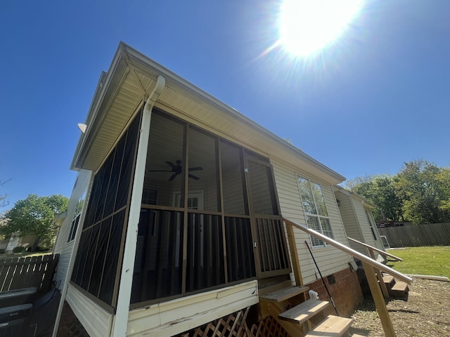 view of side of home with fence, ceiling fan, a sunroom, and crawl space
