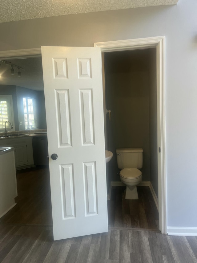 bathroom featuring toilet, track lighting, a sink, and wood finished floors