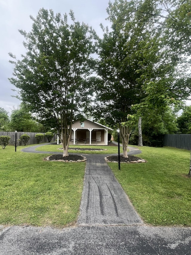 view of property hidden behind natural elements with fence and a front lawn