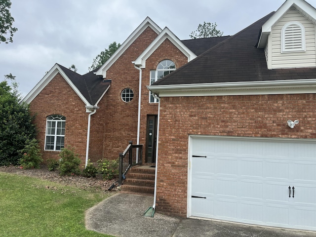 traditional home featuring a shingled roof and brick siding