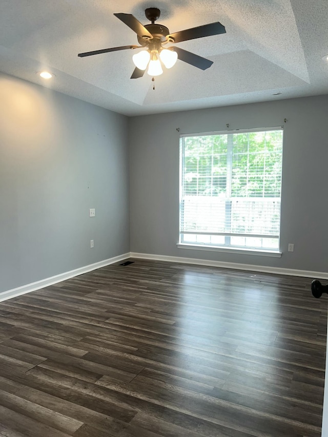 empty room featuring ceiling fan, a textured ceiling, dark wood finished floors, and baseboards
