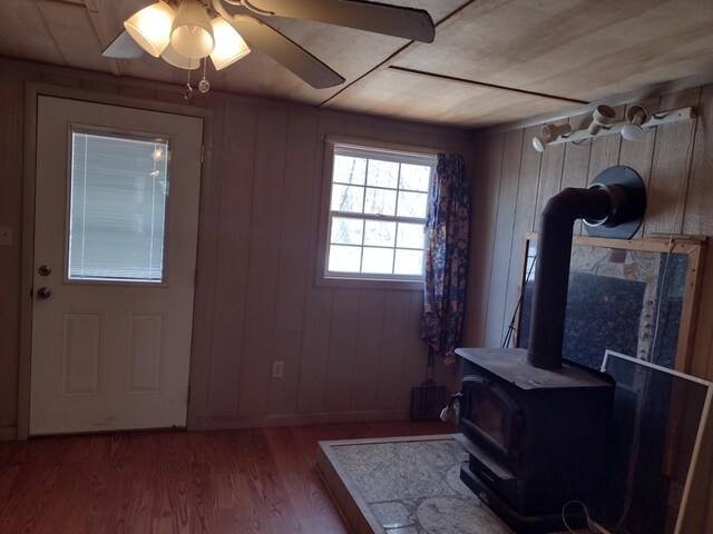 interior space with a ceiling fan, wood finished floors, and a wood stove