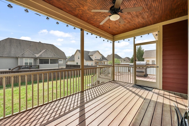 deck with a ceiling fan, fence, a yard, and a residential view
