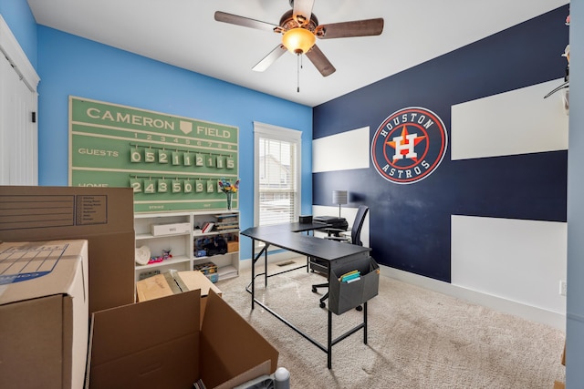 office space featuring baseboards, carpet, an accent wall, and a ceiling fan
