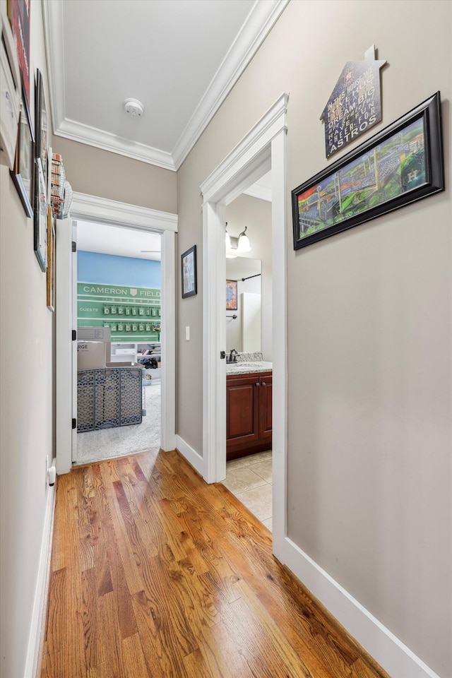 hall with ornamental molding, baseboards, and light wood-style floors