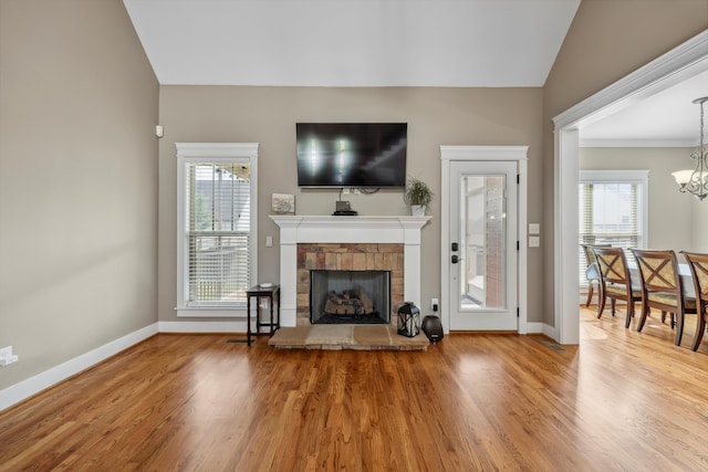 living area with plenty of natural light, baseboards, a stone fireplace, and wood finished floors