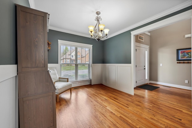 unfurnished room featuring a wainscoted wall, ornamental molding, a chandelier, and light wood-type flooring