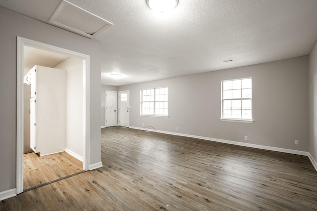 unfurnished room featuring attic access, baseboards, wood finished floors, and a textured ceiling