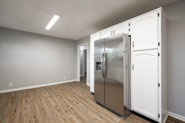kitchen featuring white cabinets, stainless steel fridge, baseboards, and light wood finished floors